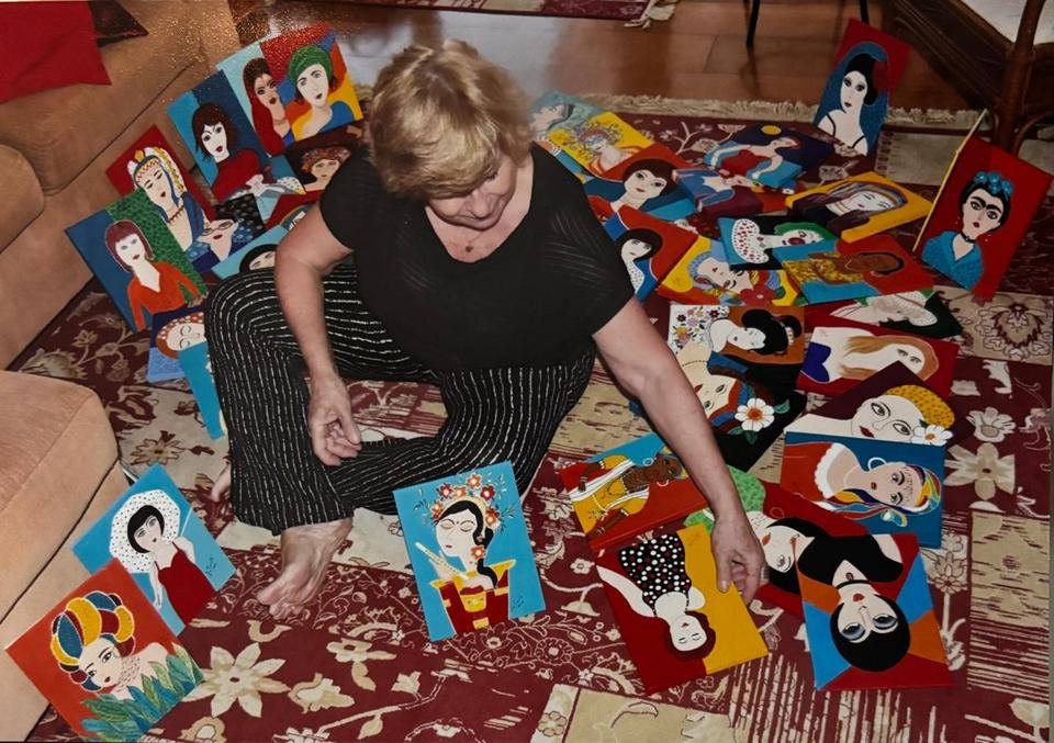 La Pimenta sentada no chão entre dezenas das suas pinturas